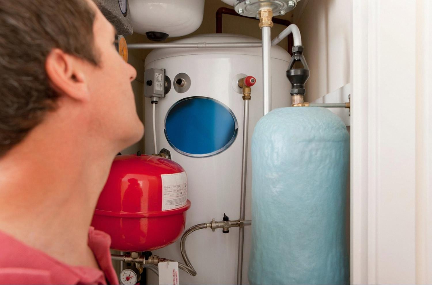 Plumber inspecting a residential water heater and pressure tank in a UAE apartment